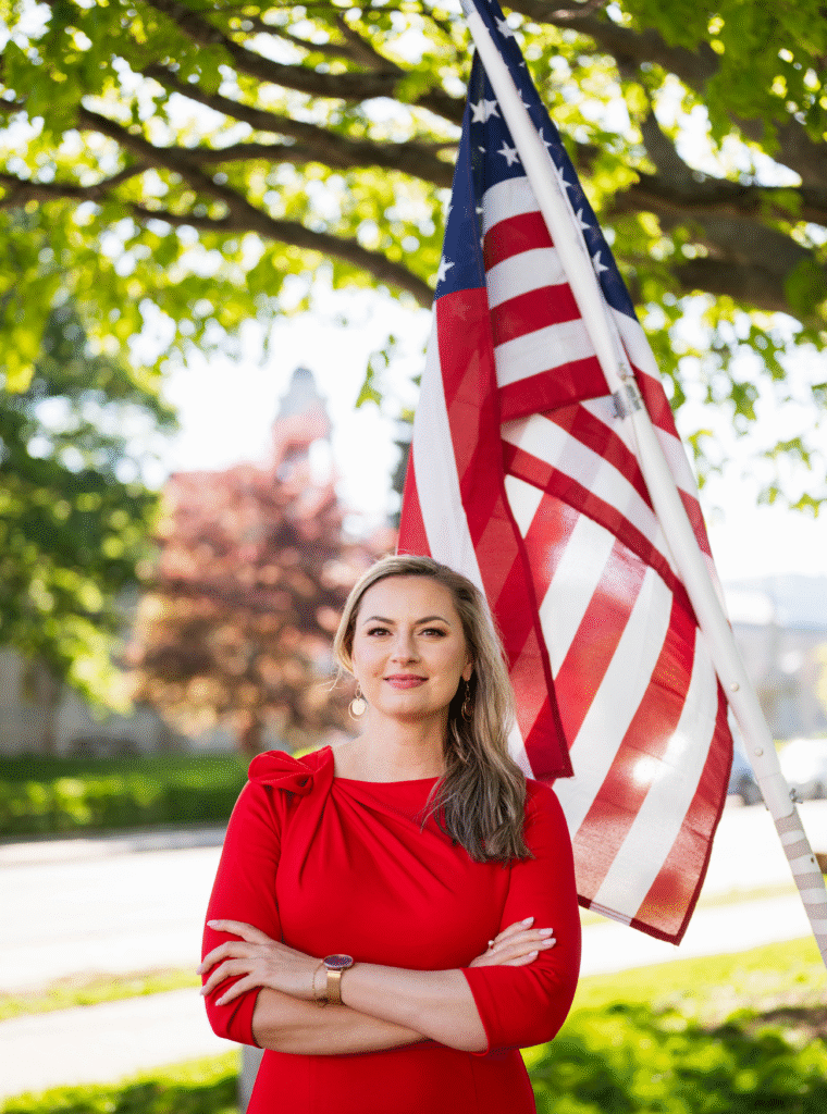 Aga Asbury a Maine based immigration attorney standing in front of an American flag
