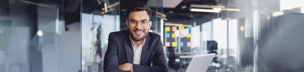 An immigration lawyer smiling at his desk while handling visa processes